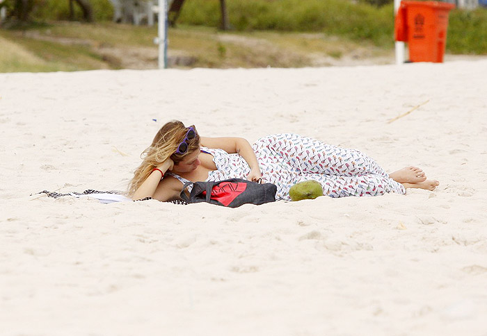 De vestido longo, Juliana Didone relaxa na praia da Barra da Tijuca