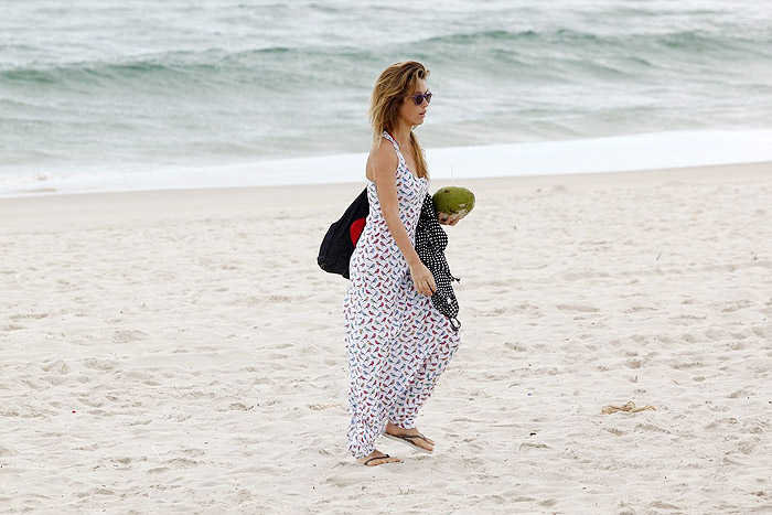 De vestido longo, Juliana Didone relaxa na praia da Barra da Tijuca