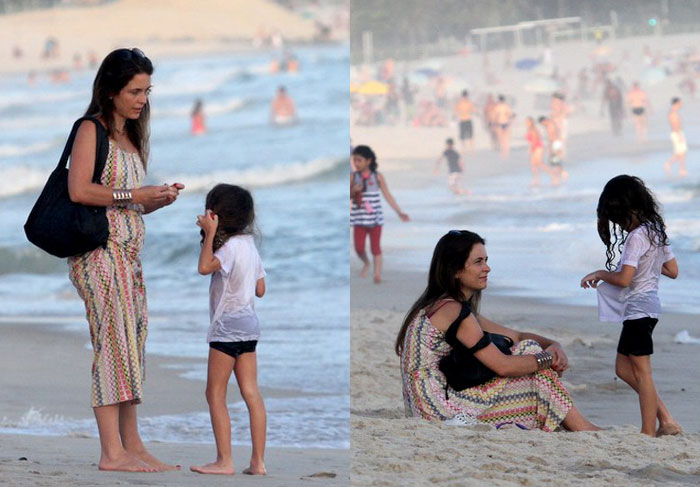 De vestido comprido, Claudia Abreu leva filha à praia