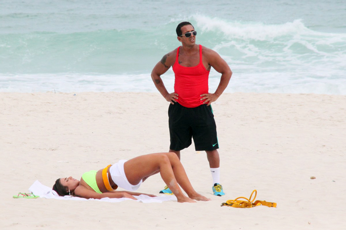 Com sainha branca, Nicole Bahls se exercita na praia