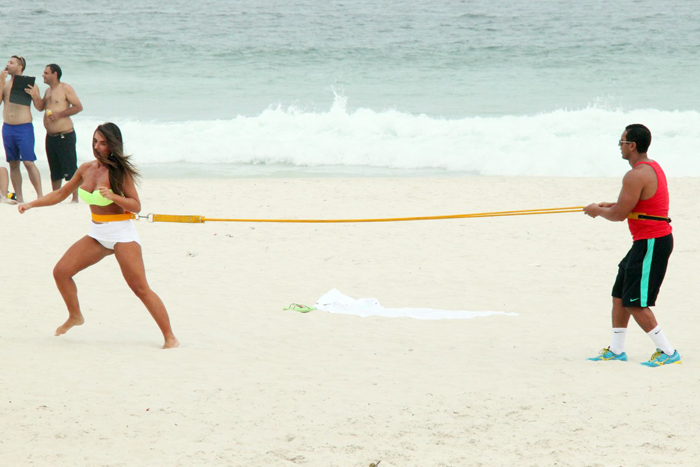 Com sainha branca, Nicole Bahls se exercita na praia