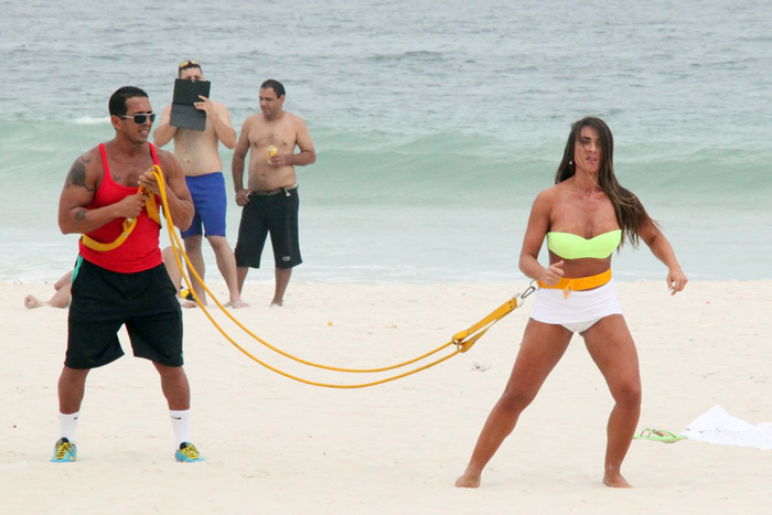 Com sainha branca, Nicole Bahls se exercita na praia