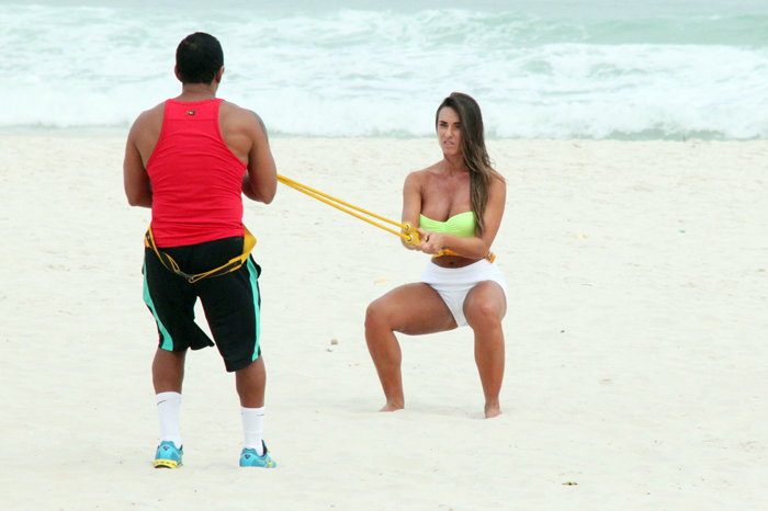 Com sainha branca, Nicole Bahls se exercita na praia