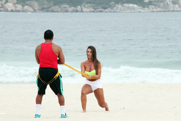 Com sainha branca, Nicole Bahls se exercita na praia