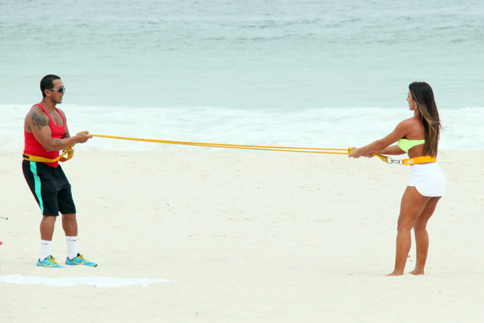 Com sainha branca, Nicole Bahls se exercita na praia