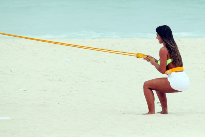 Com sainha branca, Nicole Bahls se exercita na praia