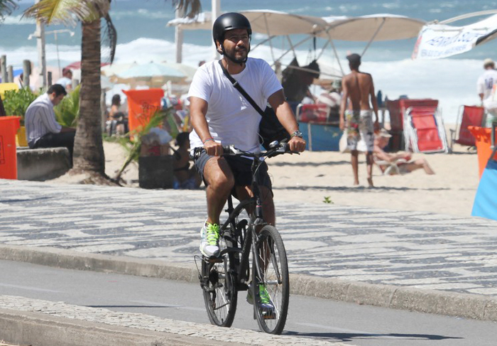 Protegido por um capacete, Marcos Palmeira anda de bike na orla