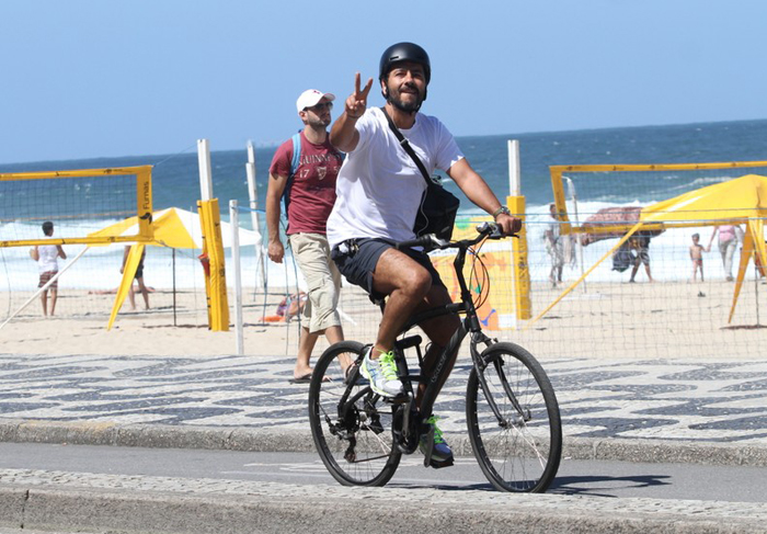 Protegido por um capacete, Marcos Palmeira anda de bike na orla