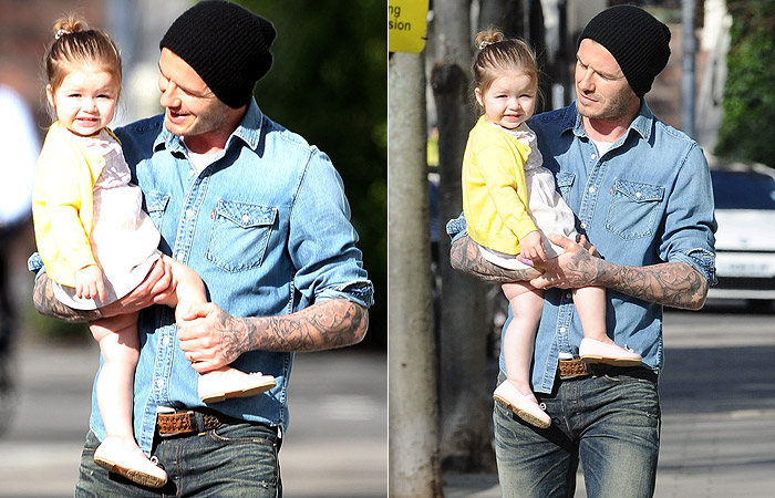 Harper Beckham sorri para paparazzo enquanto pega carona no colo do pai David Beckham