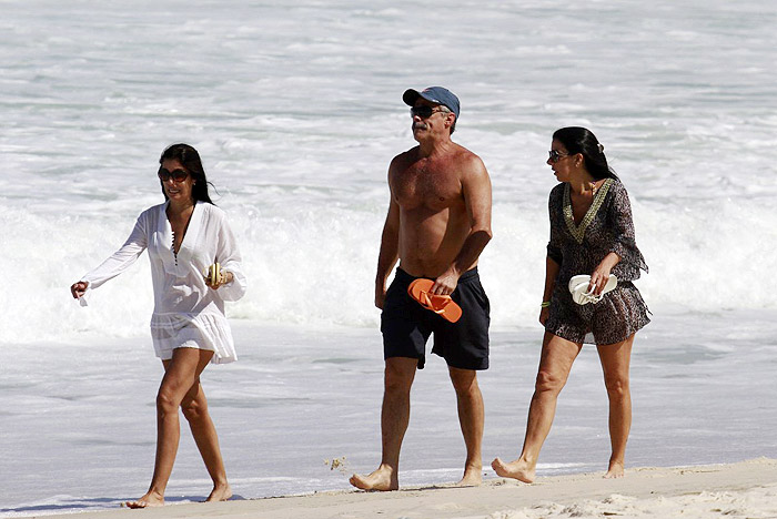 Oscar Magrini anda na praia acompanhado de duas mulheres