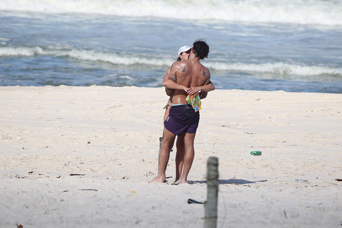 Juliano Cazarré troca beijos com a esposa na praia