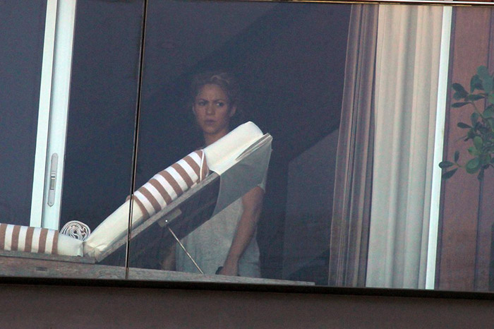Shakira olha atentamente pela janela do hotel, no Rio