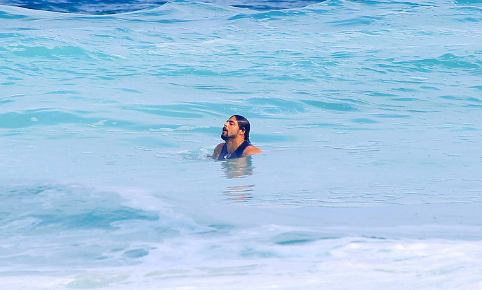 Cauã Reymond deixa a prancha de lado e nada na praia da Barra