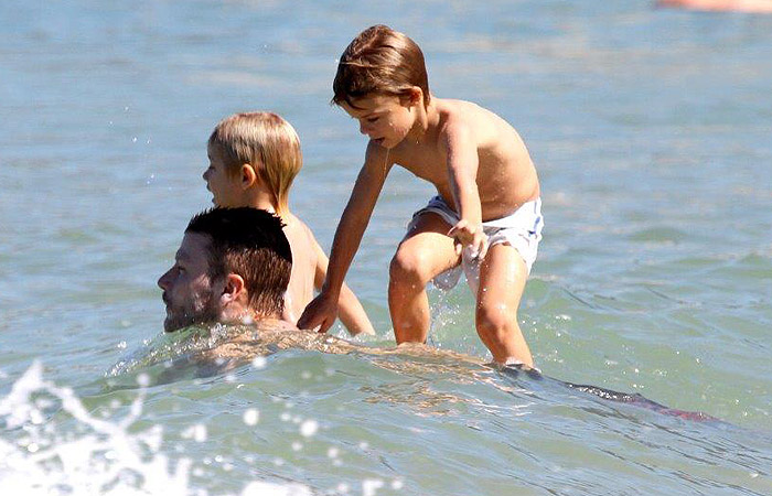 Rodrigo Hilbert vira prancha de surfe em farra com os filhos no mar