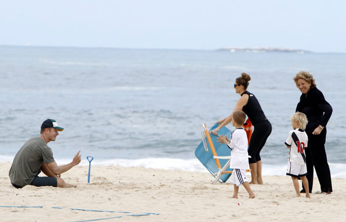 Fernanda Lima toma chimarrão na praia enquanto os filhos se divertem