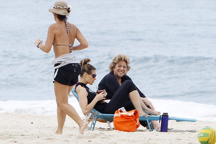 Fernanda Lima toma chimarrão na praia enquanto os filhos se divertem