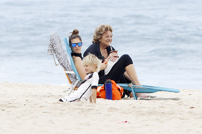 Fernanda Lima toma chimarrão na praia enquanto os filhos se divertem