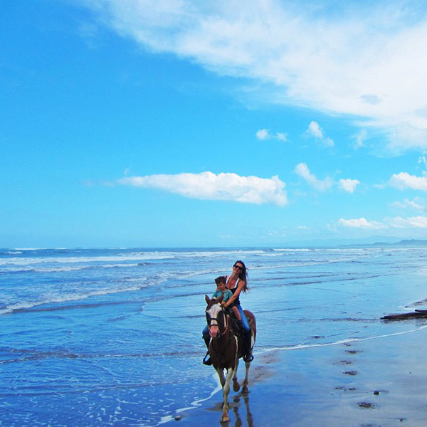 Gisele Bündchen cavalga com o filho na praia