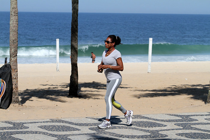 Glória Maria caminha sorridente pela orla de Ipanema