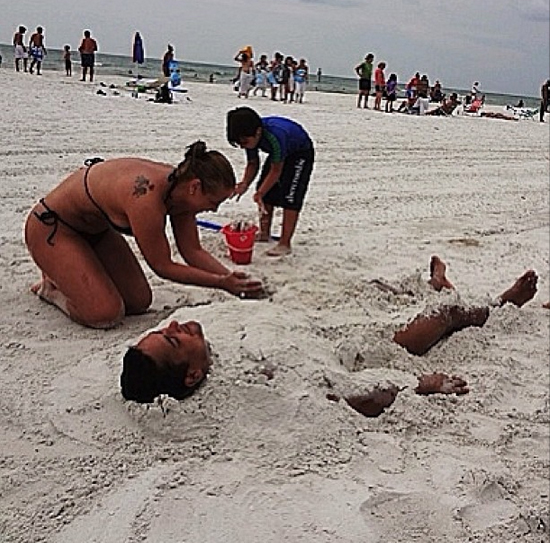 Carla Perez enterra omarido Xanddy na areia da praia
