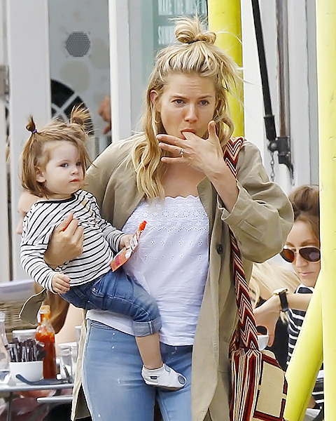 Sienna Miller lambe os dedos enquanto caminha com a filha em Londres