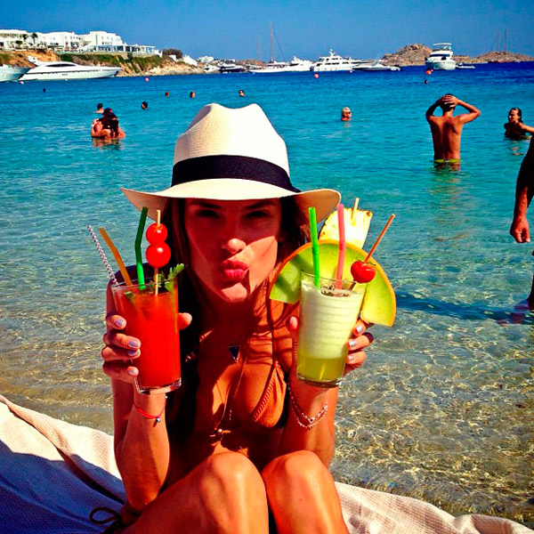 Alessandra Ambrosio bebe dois drinks ao mesmo tempo na Grécia