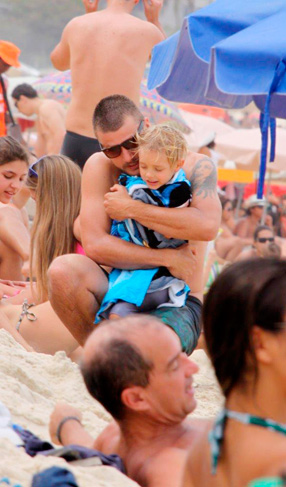 Rodrigo Hilbert abraça um de seus filhos na areias da praia