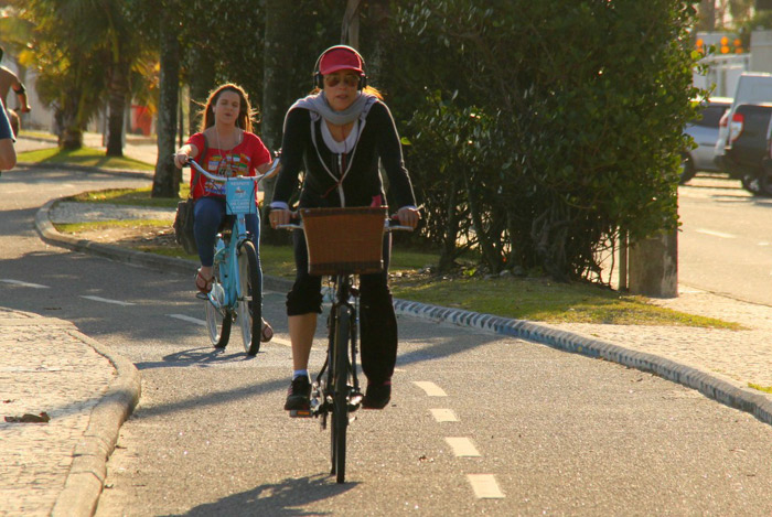 De boné e cachecol, Christiane Torloni pedala em orla carioca