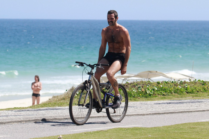 Com barba estilosa, Iran Malfitano anda de bike em praia carioca