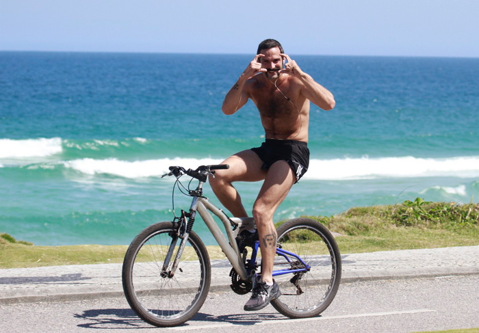 Com barba estilosa, Iran Malfitano anda de bike em praia carioca