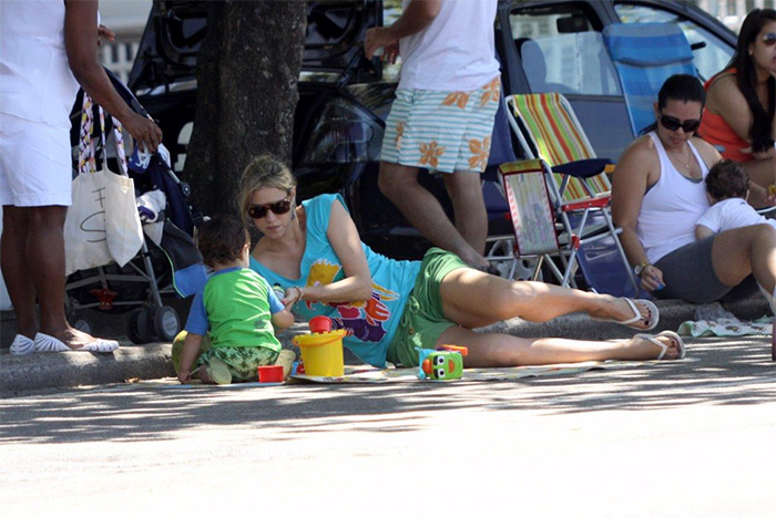 Luana Piovani senta no chão da orla para brincar com o filho