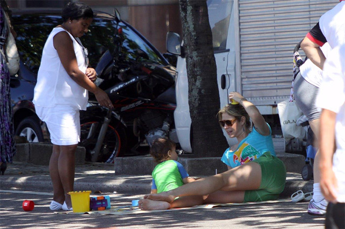 Luana Piovani senta no chão da orla para brincar com o filho