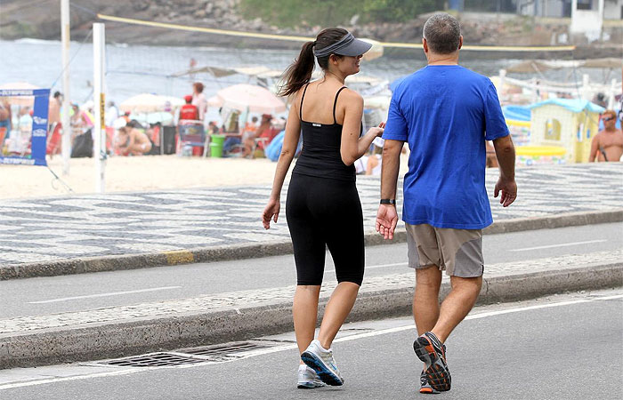 Patrícia Poeta caminha pela orla da praia com o marido
