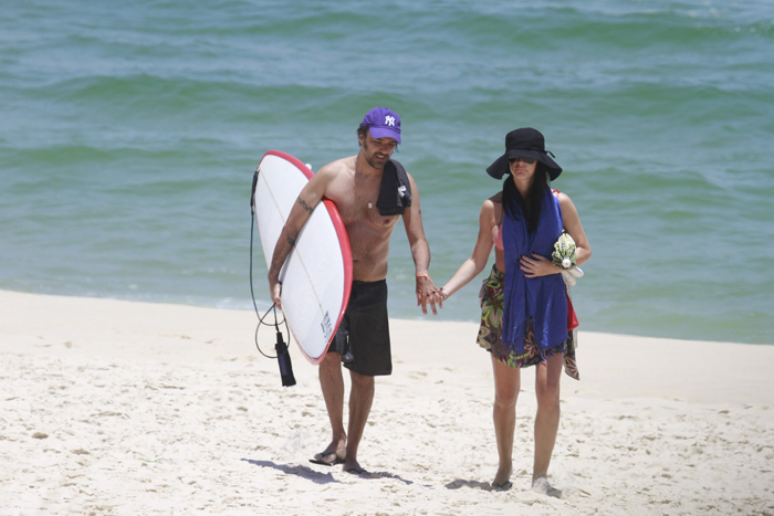 Alinne Moraes usa chapelão para ir à praia com o namorado