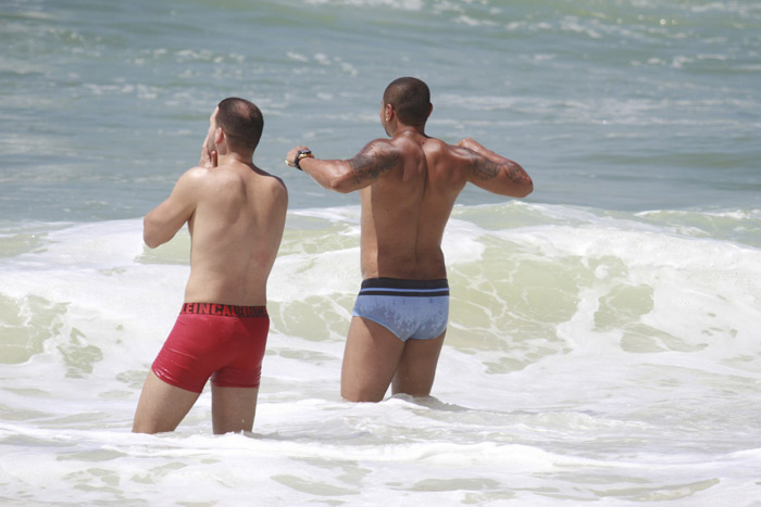 De sunga azul, Naldo se refresca na praia da Barra