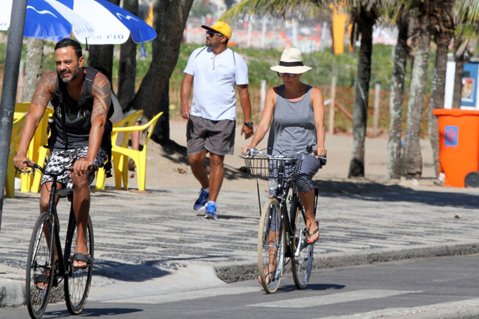 Carolina Ferraz passeia de bicicleta com o namorado na praia de Ipanema