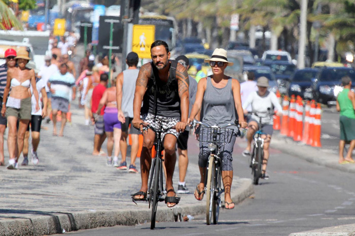 Carolina Ferraz passeia de bicicleta com o namorado na praia de Ipanema