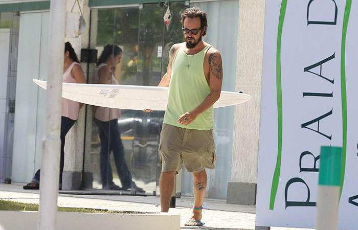 Paulo Vilhena sai de loja de surfe com prancha na mão