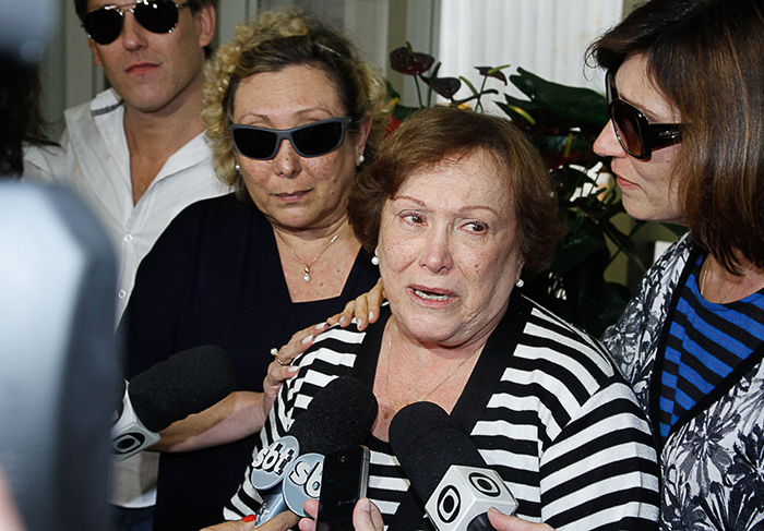 Nicette Bruno fala com a imprensa na porta do hospital, amparada pelos filhos