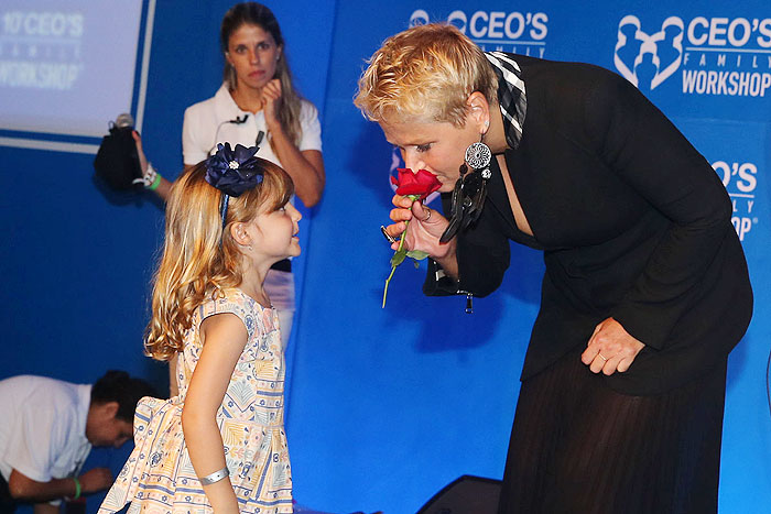 Xuxa cheira rosa e entrega a criança durante a CEOs Family Workshop em Guarujá,