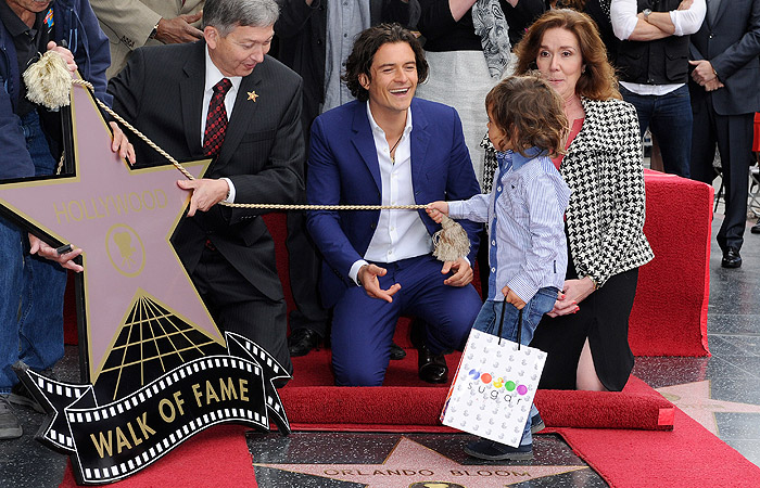 Orlando Bloom posa com o filho ao ganhar estrela na Calçada da Fama