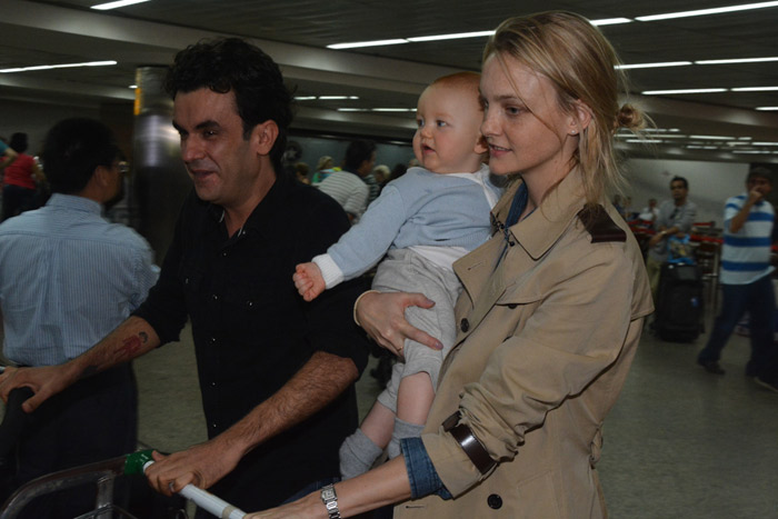 Carol Trentini desembarca em aeroporto de SP com o filho no colo