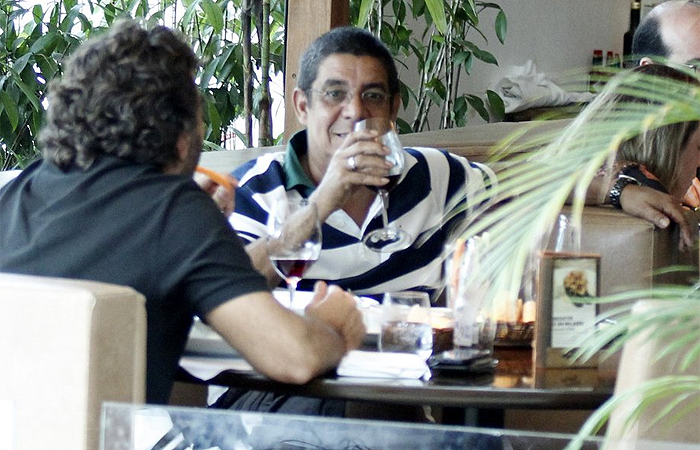 Zeca Pagodinho mostra para fotógrafo que está bebendo água em restaurante