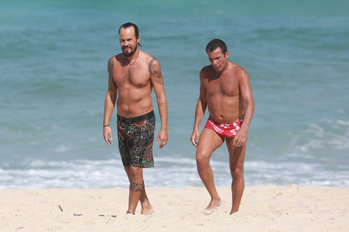 Paulo Vilhena e Eri Johnson caminham juntos em praia carioca