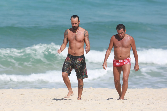 Paulo Vilhena e Eri Johnson caminham juntos em praia carioca