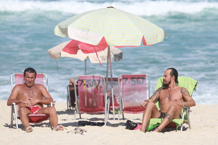 Paulo Vilhena e Eri Johnson caminham juntos em praia carioca