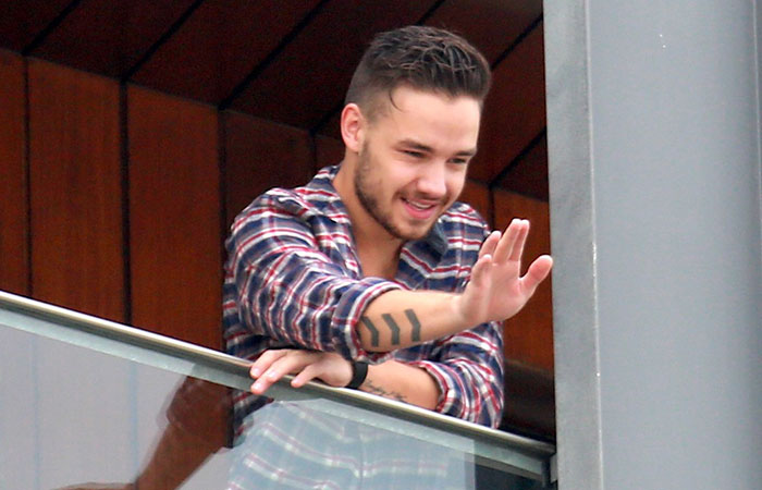 Liam Payne acena para fãs na sacada do hotel, no Rio