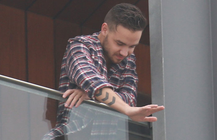 Liam Payne acena para fãs na sacada do hotel, no Rio