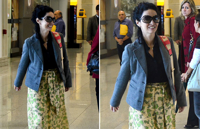 Cláudia Ohana embarca sorridente no aeroporto Santos Dumont