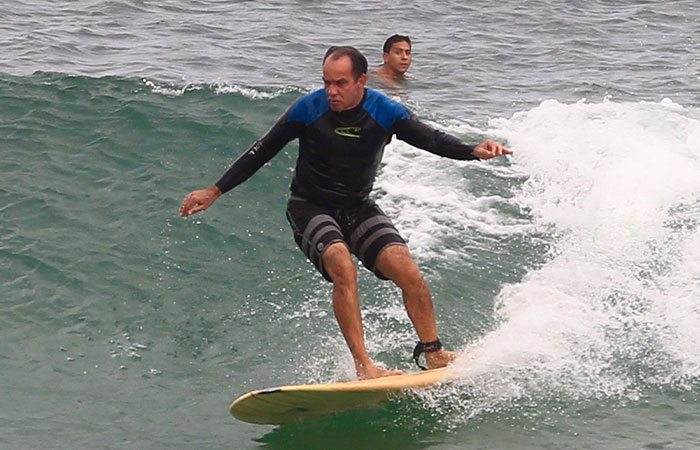 Humberto Martins troca de roupa na praia antes de surfar